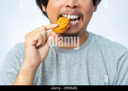 Mann, der frittierte tempe mit weißem Hintergrund isst. Traditionelles indonesisches Essen Stockfoto