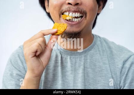 Mann, der frittierte tempe mit weißem Hintergrund isst. Traditionelles indonesisches Essen Stockfoto