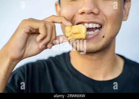 Mann, der Gorengan mit weißem Hintergrund isst. Traditionelles indonesisches Essen Stockfoto