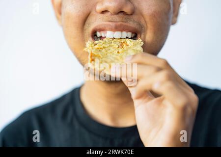 Mann, der Gorengan mit weißem Hintergrund isst. Traditionelles indonesisches Essen Stockfoto