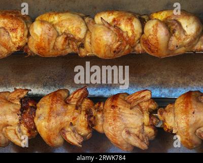 Mehrere knusprige braune Hühner auf einem rotierenden Grill, Detail Stockfoto