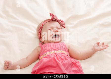 Weinen und Gestikulieren zehn Wochen alten Babymädchen auf Bett Stockfoto