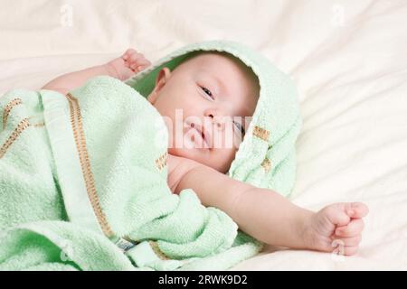 Zehn Wochen alte süße kleine Baby Mädchen Kleinkind in Handtuch Strecken den Arm gewickelt Stockfoto