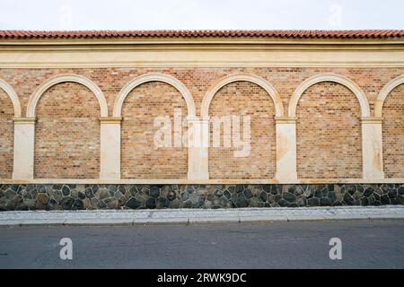 Klassische, dekorative Mauer mit Säulen, Bögen und steinernen Sockel neben dem Bürgersteig und Straße Stockfoto