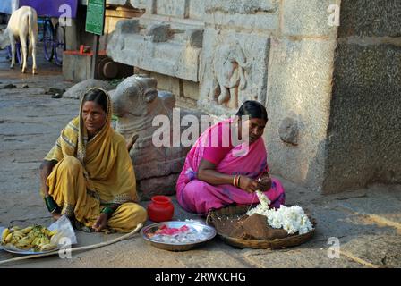 Indische Frauen, die Blumen und Bananen zum Verkauf anbieten, Hampi, Karnataka, Südindien Stockfoto
