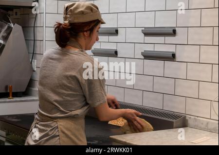 Ein Pizzaiolo ist ein Küchenchef, der auf die Zubereitung echter italienischer Pizzen spezialisiert ist und mit der Zubereitung und dem Backen frisch gebackener halbgroßer Pizzen in einer der Ma beschäftigt ist Stockfoto