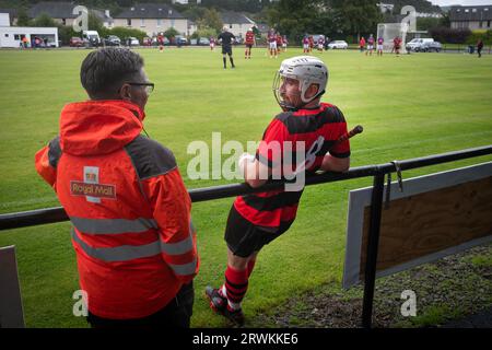 SpOne der Heimspieler plauderte während einer Spielpause mit einem Zuschauer, während Oban Camanachd Kingussie in einem glanzvollen Spiel der Premiership im Mossfield Park in Oban spielt. Die Heimmannschaft wurde 1889 gegründet und war schon immer einer der führenden Vereine in diesem Sport, der fast ausschließlich in Schottland spielte. Die Besucher gewannen diese Begegnung in der obersten Liga mit 2 Toren zu 1, beobachtet von einer Menge von rund 100 Zuschauern. Stockfoto