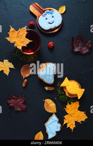 Herbsttee. Tasse Tee, bemalte Lebkuchen, Eicheln und Blätter auf schwarzem Hintergrund. Stockfoto