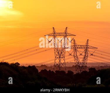 Hochspannungstürme in einem atemberaubenden Sonnenuntergang Stockfoto