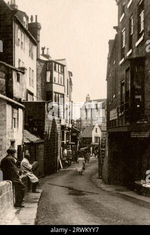 Das Zentrum des lebhaften englischen Dorfes im Jahr 1926, Robin Hoods Bay an der North Yorkshire Coast. Vintage-Fotografie aus einer Sammlung von Yorkshire-Familien. Auf der rechten Seite befindet sich ein Kartenfachgeschäft. Stockfoto