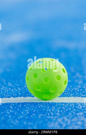 Grüner Pickleball-Ball isoliert auf einem blauen Platz Stockfoto