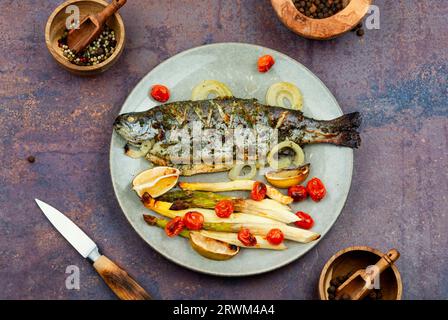 Gegrillte ganze Forelle, gekocht mit Spargel. Gebackener Lachsfisch, serviert auf einem Teller Stockfoto