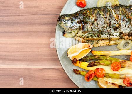 Gegrillte Forelle mit Spargel. Gebackener Lachsfisch auf Holztisch. Leerzeichen kopieren. Stockfoto