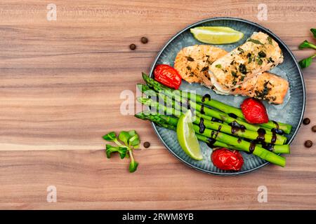 Gesundes Mittagessen mit Forelle, Spargel und Tomate auf einem Holztisch. Stockfoto