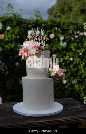 Eine köstliche Hochzeitstorte mit Blumen auf einem Holztisch im Freien Stockfoto