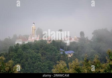 Eine Silhouette einer stehenden Buddha-Statue im Wat Phrathat Doi Kham in Thailand an einem nebligen Tag Stockfoto