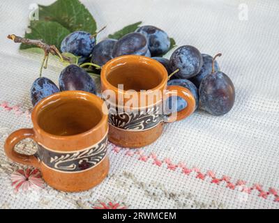 Zwei Porzellan-Kaffeetassen auf einer Tischdecke mit einem Pflaumenzweig Stockfoto