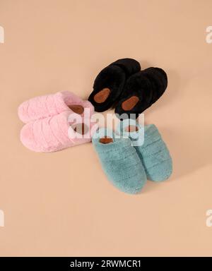 Drei Paar Hausschuhe, die in einem Stapel angeordnet sind, der auf dem Boden vor einer weißen Wand liegt Stockfoto