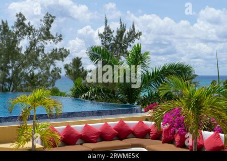 Tropische Blumenterrasse mit offener Lounge und Infinity-Pool mit Blick auf das Karibische Meer in Mexiko Stockfoto