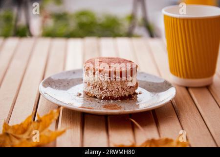 Gesundes Karottendessert mit Agavensirup. Kuchen mit einer Tasse Kaffee unter harten Schatten. Frühstück im Freien. Stockfoto