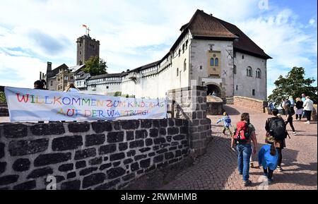 Eisenach, Deutschland. September 2023. „Willkommen zum Kindertag auf der Wartburg“ steht auf einem Banner vor dem Eingang zur Wartburg. Am Weltkindertag wird der neue Abenteuer- und Wissensweg „Eselei“ an der ehemaligen Eselstation unterhalb der Wartburg eröffnet. An zehn Stationen auf rund 300 Metern Waldweg erfahren die Besucher interessante Fakten über den Thüringer Löwen, Martin Luther, die Heilige Elisabeth und andere Akteure und Ereignisse der Wartburger Geschichte. Quelle: Martin Schutt/dpa/Alamy Live News Stockfoto