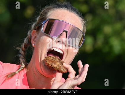 20. September 2023, Brandenburg, Reitwein: Joyce Hübner, Athletin, isst während einer Pause auf ihrer letzten Etappe der Tour durch Deutschland entlang der deutsch-polnischen Grenze oder ein Boulette. Joyce Hübner wird von weiteren Läufern begleitet. Das Ziel ist für den Nachmittag an der Stadtbrücke in Frankfurt (oder) geplant. Joyce Hübner hat nun 120 Marathons hintereinander gelaufen und eine Strecke von 5.200 Kilometern entlang der deutschen Grenze zurückgelegt. Mit diesem Projekt möchte der Extremsportler andere Menschen dazu inspirieren, ihre Komfortzone zu verlassen und zu zeigen, wie das Testen Ihrer persönlichen Grenzen nachhaltig positive Auswirkungen auf Sie haben kann. Stockfoto