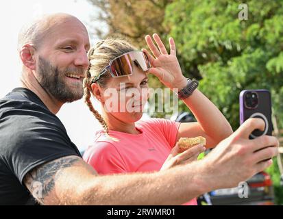 20. September 2023, Brandenburg, Reitwein: Joyce Hübner, Athletin, dreht zusammen mit Thomas, Mitläufer, ein Video während einer Pause auf der letzten Etappe der Tour durch Deutschland auf dem Deich an der deutsch-polnischen Grenze der oder. Joyce Hübner wird von weiteren Läufern begleitet. Das Ziel ist für den Nachmittag an der Stadtbrücke in Frankfurt (oder) geplant. Joyce Hübner hat nun 120 Marathons hintereinander gelaufen und eine Strecke von 5.200 Kilometern entlang der deutschen Grenze zurückgelegt. Mit diesem Projekt möchte der Extremsportler andere Menschen dazu inspirieren, ihre Komfortzone zu verlassen und zu zeigen, wie er Ihre persönliche Limette testet Stockfoto