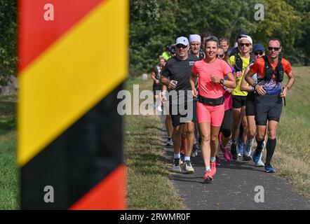 20. September 2023, Brandenburg, Reitwein: Joyce Hübner (Mittelfront), Athletin, ist auf ihrer letzten Etappe der Tour of Germany auf dem Deich entlang der deutsch-polnischen Grenzfluss oder in Richtung Frankfurt (oder). Joyce Hübner wird von weiteren Läufern begleitet. Das Ziel ist für den Nachmittag an der Stadtbrücke in Frankfurt (oder) geplant. Joyce Hübner hat nun 120 Marathons hintereinander gelaufen und eine Strecke von 5.200 Kilometern entlang der deutschen Grenze zurückgelegt. Mit diesem Projekt möchte der Extremsportler andere Menschen dazu inspirieren, ihre Komfortzone zu verlassen und zu zeigen, wie das Testen Ihrer persönlichen Grenzen eine dauerhafte Wirkung haben kann Stockfoto