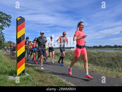 20. September 2023, Brandenburg, Reitwein: Joyce Hübner (r), Athletin, ist auf ihrem letzten Abschnitt der Tour of Germany auf dem Deich entlang der deutsch-polnischen Grenzfluss oder in Richtung Frankfurt (oder). Joyce Hübner wird von weiteren Läufern begleitet. Das Ziel ist für den Nachmittag an der Stadtbrücke in Frankfurt (oder) geplant. Joyce Hübner hat nun 120 Marathons hintereinander gelaufen und eine Strecke von 5.200 Kilometern entlang der deutschen Grenze zurückgelegt. Mit diesem Projekt möchte der Extremsportler andere Menschen dazu inspirieren, ihre Komfortzone zu verlassen und zu zeigen, wie das Testen Ihrer persönlichen Grenzen eine dauerhaft positive wirkung haben kann Stockfoto