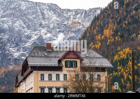 Gebäude mit Alpenbergen im Hintergrund - schneebedeckt und herbstlich bewachsen - Hallstatt, Österreich Stockfoto