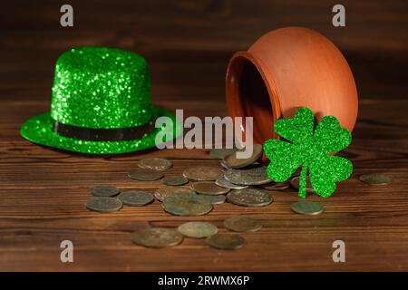 St. Patricks Tageskonzept mit Topf mit verstreuten alten Münzen, grünem Hut und Schamrock auf altem hölzernem Hintergrund, Nahaufnahme. Stockfoto