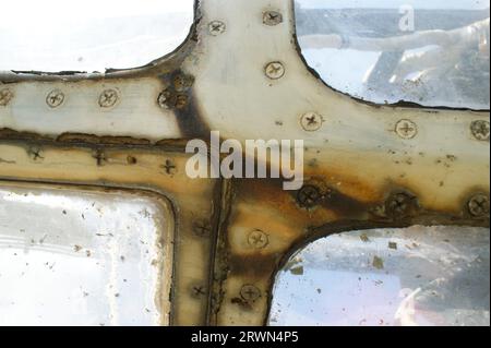 Rostiger Fensterrahmen eines alten Flugzeugs mit Schrauben. Fragment eines Flugzeugs. Stockfoto