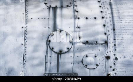 Fragment eines alten Flugzeugrumpfes. Metallischer Hintergrund mit Nieten und Schrauben. Stockfoto