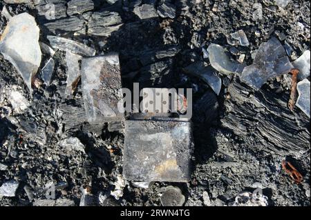 Öffnen Sie den alten Zippo-Feuerzeug. Brandfolgen. Verbranntes Metallfeuerzeug in Asche. Stockfoto