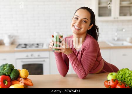 Arabische Dame in Sportbekleidung hält Glas mit Smoothie in der Küche Stockfoto