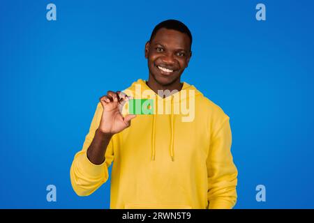 Glücklicher gutaussehender junger Schwarzer zeigt Kreditkarte, empfiehlt Finanzersparnisse Stockfoto
