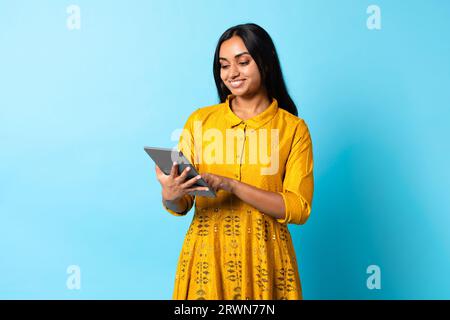 Indische Dame In Traditionellem Kleid Mit Digitalem Tablet, Blauer Hintergrund Stockfoto
