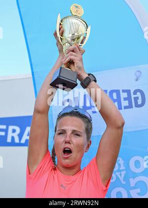 20. September 2023, Brandenburg, Frankfurt (oder): Joyce Hübner, Athletin, hält nach ihrem Abschluss der Tour of Germany eine Trophäe der Stadt Frankfurt (oder). Start und Ziel war die Stadtbrücke in Frankfurt (oder). Joyce Hübner hat nun 120 Marathons hintereinander gelaufen und eine Strecke von 5.200 Kilometern entlang der deutschen Grenze zurückgelegt. Mit diesem Projekt möchte der Extremsportler andere Menschen dazu inspirieren, ihre Komfortzone zu verlassen und zu zeigen, wie das Testen Ihrer persönlichen Grenzen nachhaltig positive Auswirkungen auf Sie haben kann. Foto: Patrick Pleul/dpa Stockfoto