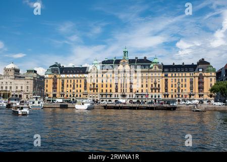 Stockholm, Schweden. Imposantes Gebäude am Ufer des Strandvagen-Ufers im Stadtteil Ostermalm. Vor Anker gelegenes Boot im Hafen, blauer Himmel Hintergrund. Stockfoto