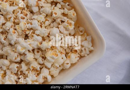 Weißes selbstgemachtes Popcorn in einer weißen Schüssel, Nahaufnahme. Eine Schüssel mit frisch gemahlenem Popcorn Stockfoto