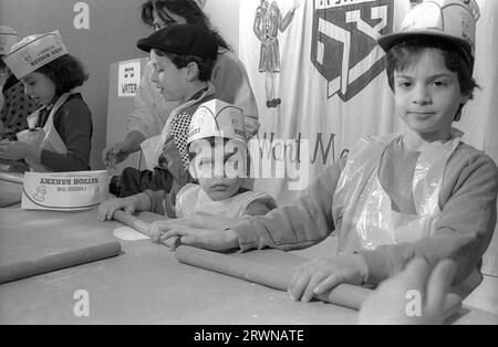 Jüdische Kinder aus den hebräischen Gemeinden Birmingham und Solihull, die im März 1991 an einer Matzo-Bäckerei vor dem PASSOVER im Lubavitch Centre in der Willows Road Birmingham teilnahmen. Den Kindern die Regeln des Backens des ungesäuerten Brotes beibringen Rabbiner Herchel Rader, Minister der Solihull-Synagoge und Professor Sam Aburdaram, Leiter der Solihull-Cheder-Schule Stockfoto