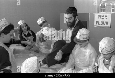 Jüdische Kinder aus den hebräischen Gemeinden Birmingham und Solihull, die im März 1991 an einer Matzo-Bäckerei vor dem PASSOVER im Lubavitch Centre in der Willows Road Birmingham teilnahmen. Den Kindern die Regeln des Backens des ungesäuerten Brotes beibringen Rabbiner Herchel Rader, Minister der Solihull-Synagoge und Professor Sam Aburdaram, Leiter der Solihull-Cheder-Schule Stockfoto