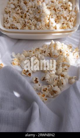 Verstreutes weißes selbstgemachtes Popcorn in einer weißen Schüssel, weißer Hintergrund, nahe up.freshly Popcorn Stockfoto