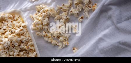 Verstreutes weißes selbstgemachtes Popcorn in einer weißen Schüssel, weißer Hintergrund, nahe up.freshly Popcorn Stockfoto