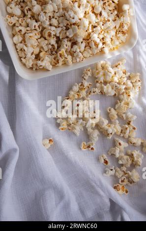 Verstreutes weißes selbstgemachtes Popcorn in einer weißen Schüssel, weißer Hintergrund, nahe up.freshly Popcorn Stockfoto