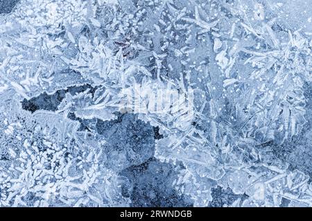 Dünnes Eis bedeckt den Winterboden, Draufsicht. Gefrorene Flussoberfläche, Makrofoto, natürliche Hintergrundtextur Stockfoto