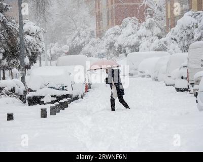 Madrid, Spanien. Januar 2021. Eine Frau mit Regenschirm und Einkaufstasche, die den Schnee auf den Straßen madrids während des Filomena-Schneefalls überquert. Stockfoto