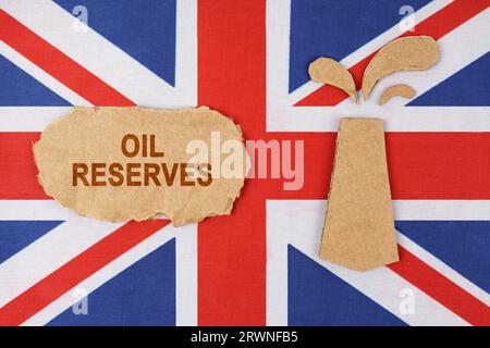 Auf der Flagge Großbritanniens befindet sich eine aus Pappe geschnittene Ölplattform und ein Schild mit der Aufschrift „Ölreserven“. Stockfoto