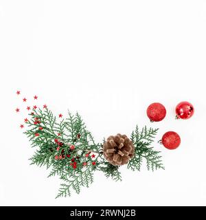 Frohe Weihnachtskomposition mit Baumzweigen und roten Kugeln mit Konfetti auf weißem Hintergrund. Flach liegend, Draufsicht Stockfoto