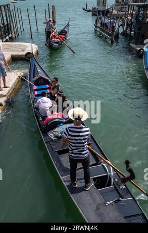 Ein Gondolier mit seinem bekannten schwarz-weiß gestreiften Hemd und Bootsfahrer ist ein Ruderer, der eine Gondel mit einem langen Ruder steuert und Touristen für eine kurze Tour nimmt Stockfoto